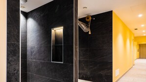 A hallway with dark marble walls, a small rectangular mirror, and a hanging light fixture. - Hotel & Restaurant Feldrand (Sarentino)