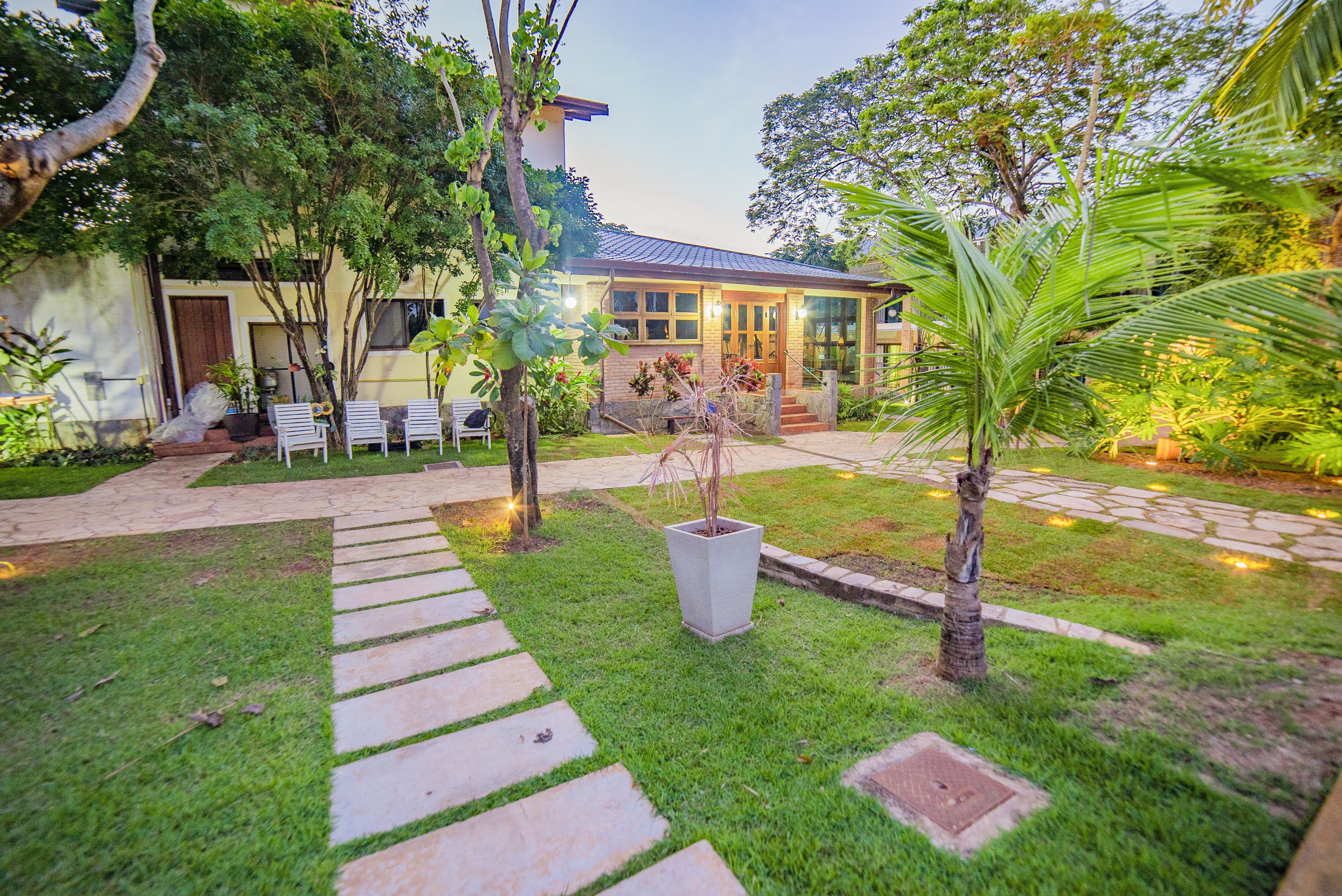 A well-maintained garden with a pathway leading to a house with a tiled roof and large windows.