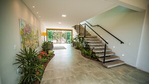 A modern staircase with a glass door leading to an outdoor area, surrounded by plants and a tiled floor. - Pousada Gira Sol (Bonito)