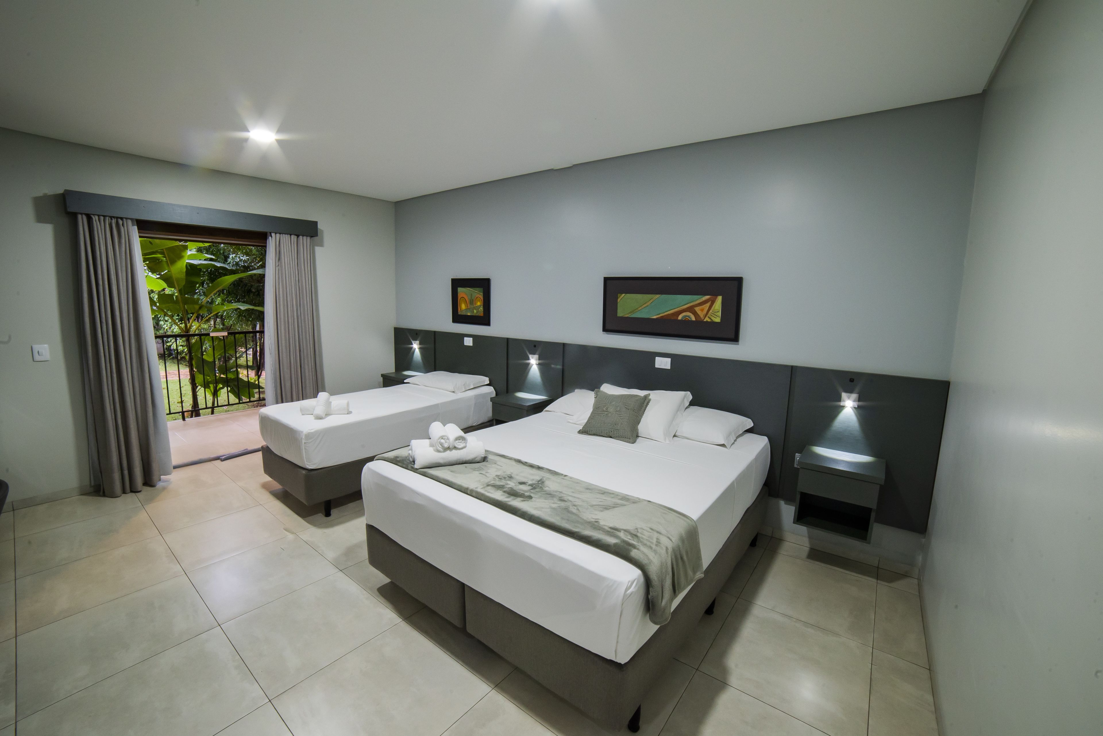 Habitación de hotel con dos camas, un balcón y obras de arte en las paredes.