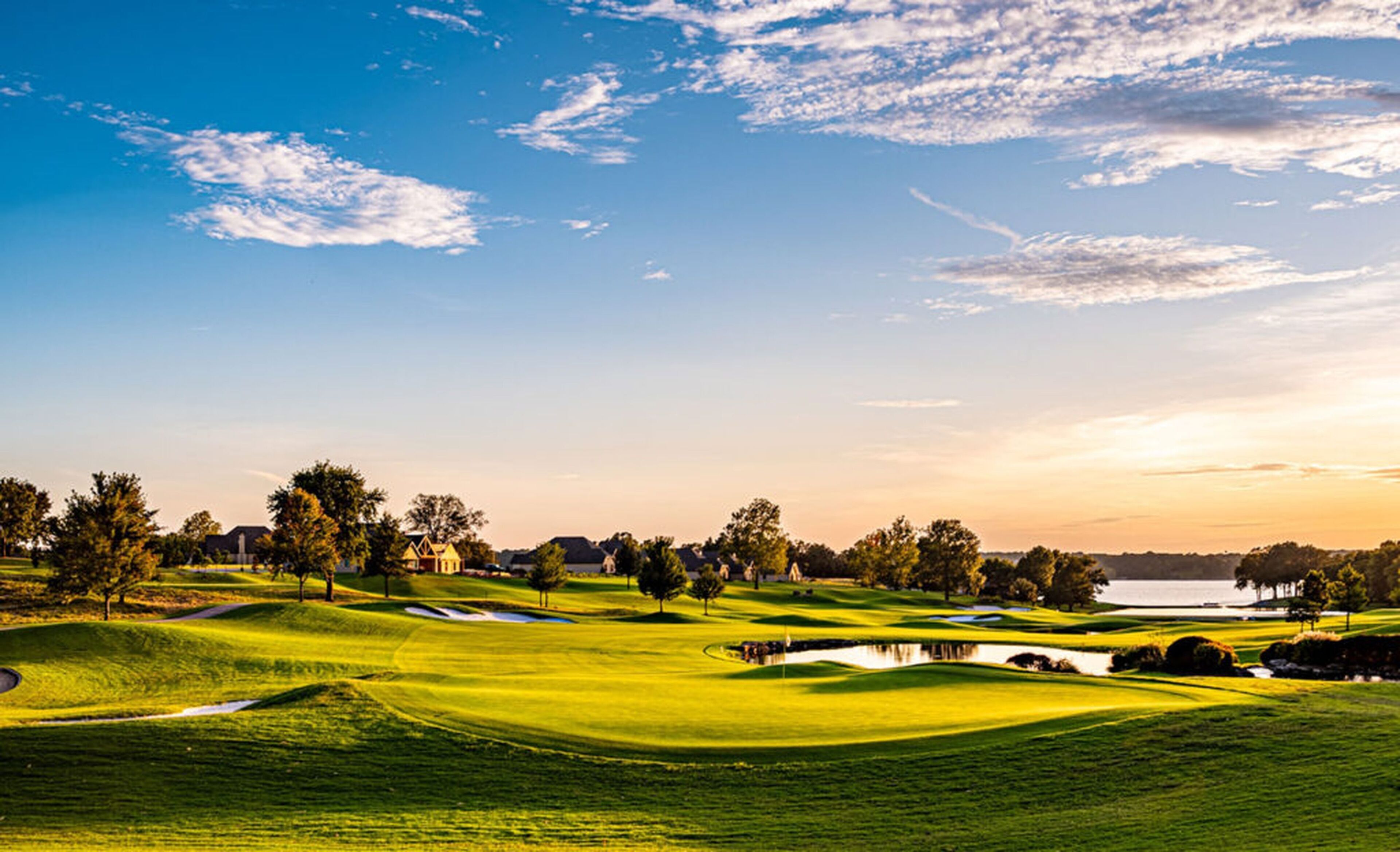 A golf course with sand bunkers, water hazards, and trees.