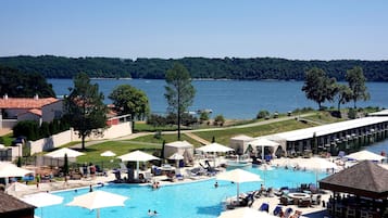 Una piscina techada, una piscina al aire libre, sombrillas