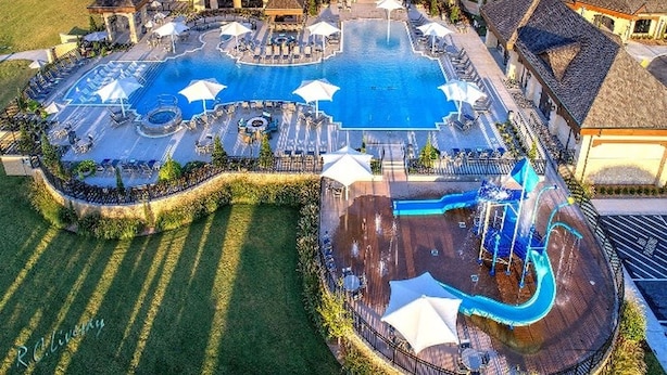 Un hotel grande con un área de piscina central, varios balcones y un césped circundante.