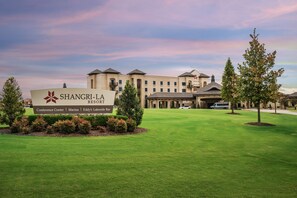 A hotel sign with amenities listed, a well-maintained lawn, and a building with a classic architectural style. - Shangri-La Resort (Afton)