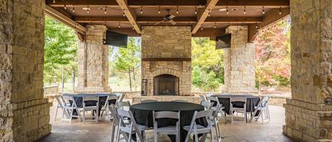 Un patio exterior con muros de piedra, una chimenea y una mesa redonda con sillas.