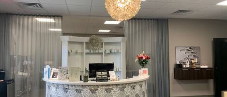 A reception area with a round counter, a large decorative light fixture, and a reception desk.