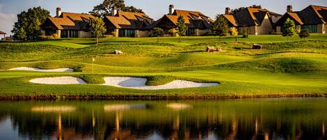 A golf course with bunkers and a pond reflecting the landscape.