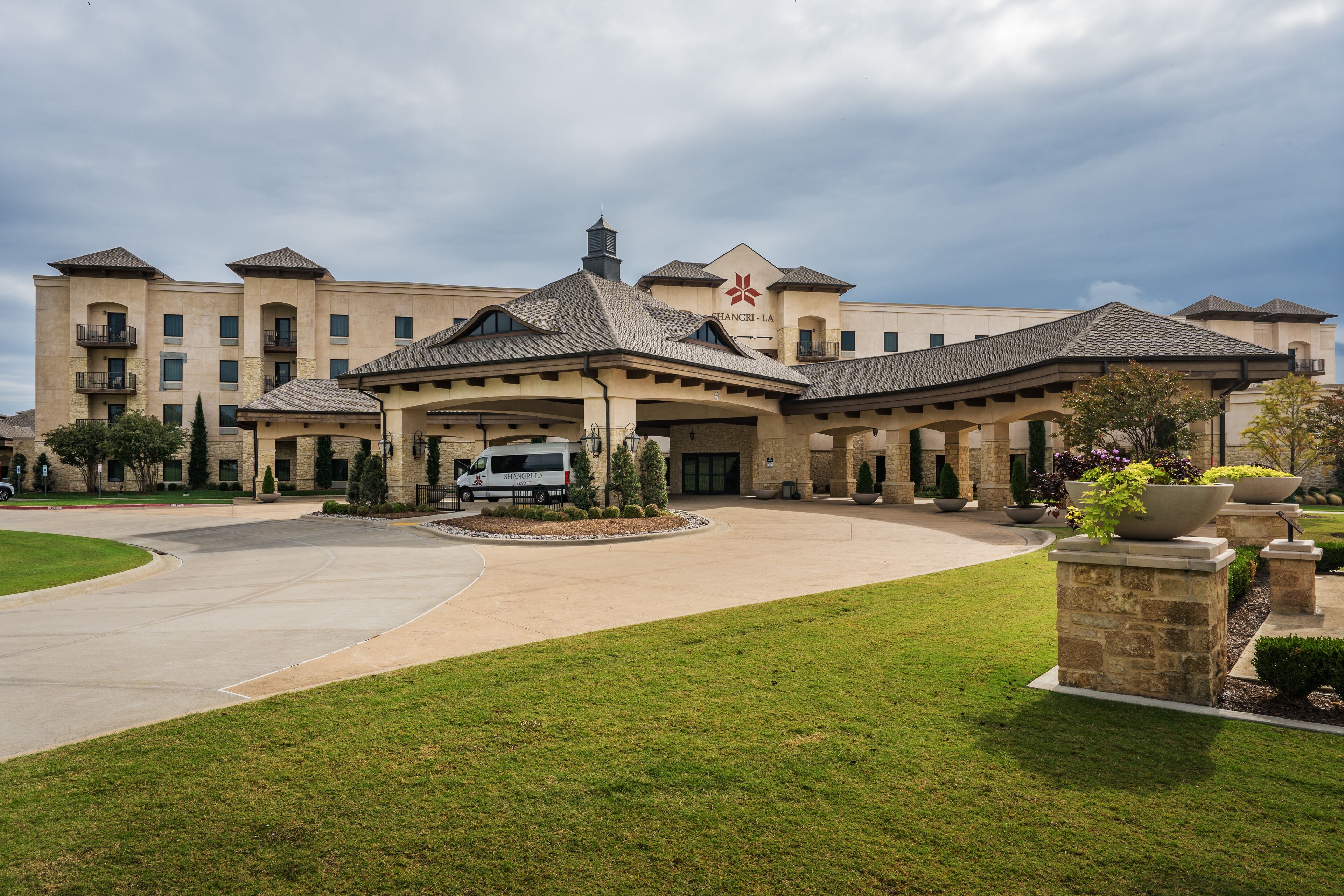 A large hotel with a central courtyard, multiple wings, and a covered entrance.