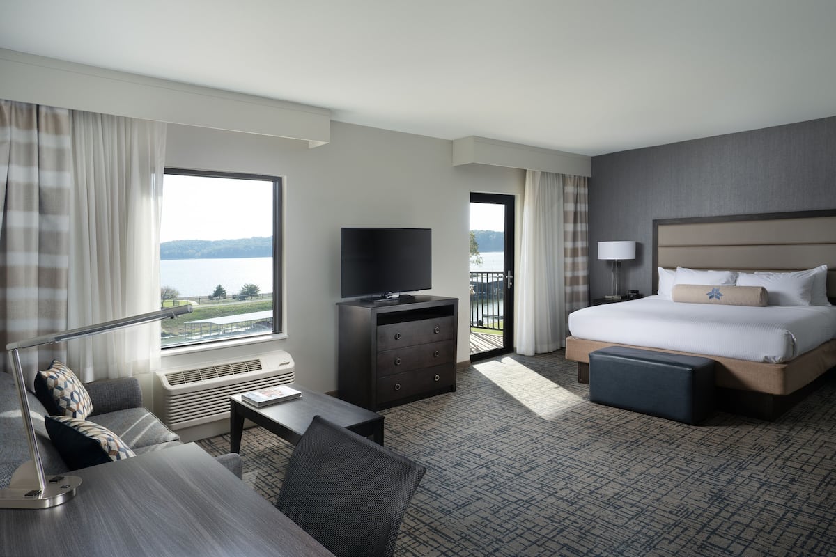 Een hotelkamer met een bed, een bureau, een televisie en uitzicht op een meer.