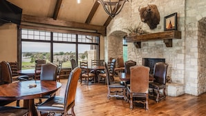 Un comedor amplio con mesas y sillas de madera, una chimenea de piedra y un gran ventanal con vistas al exterior.