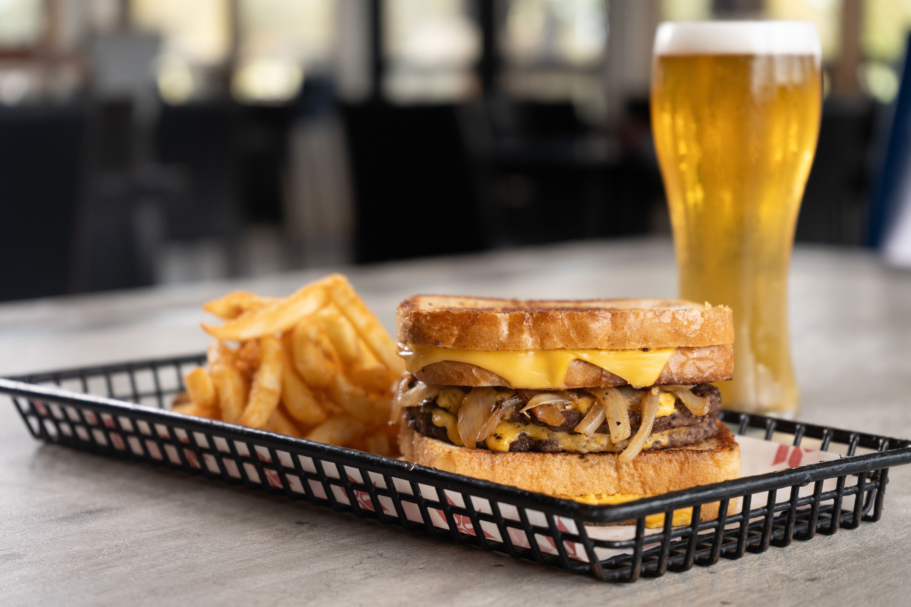 Ein Teller mit einem Sandwich, Pommes und einem Glas Bier.