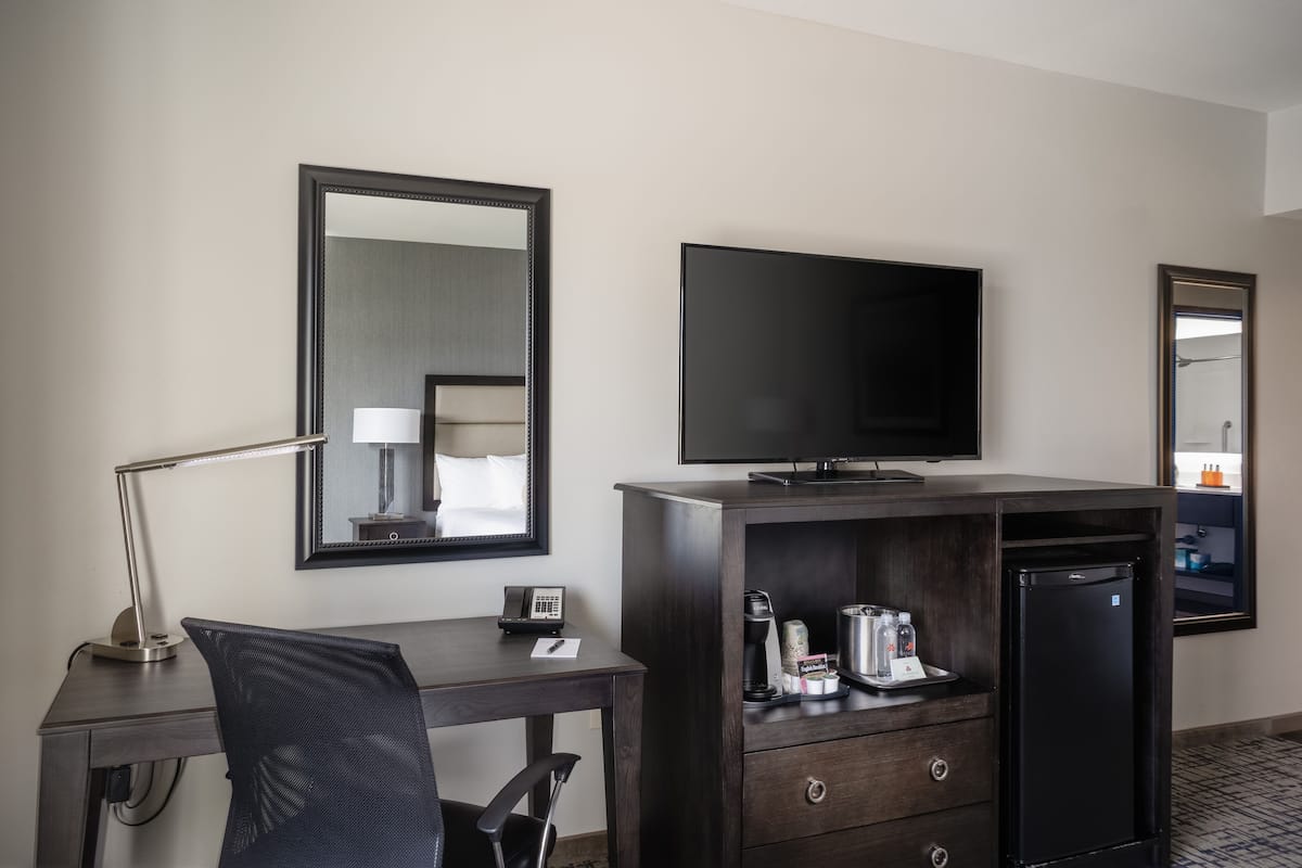 Een hotelkamer met een bureau, stoel, televisie en een minibar.