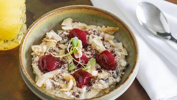 Bol de porridge amb cireres i fruits secs damunt un taulell de fusta.