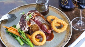 A plate of food with steak, onion rings, and vegetables.