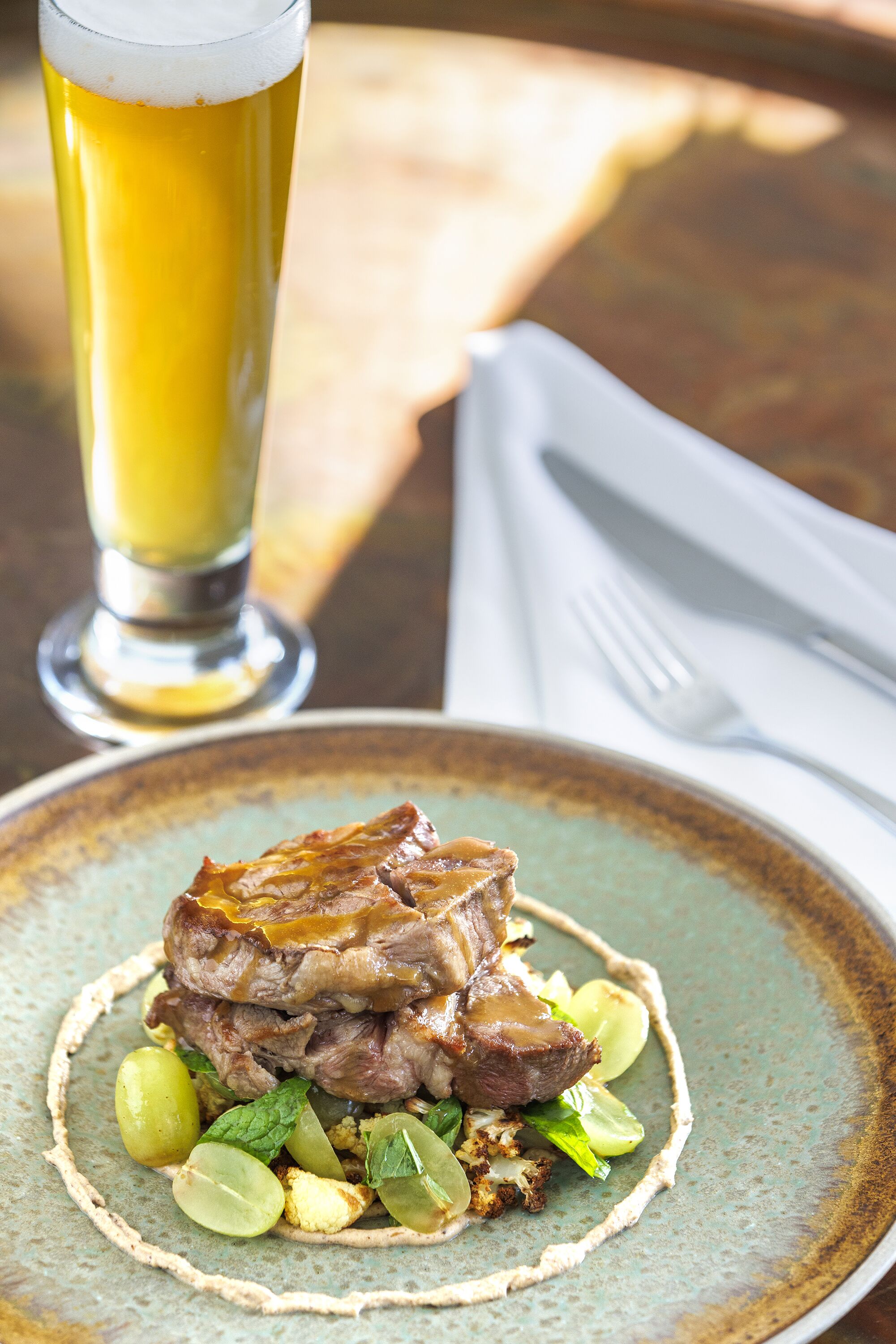 A plate of food with a glass of beer in the background.