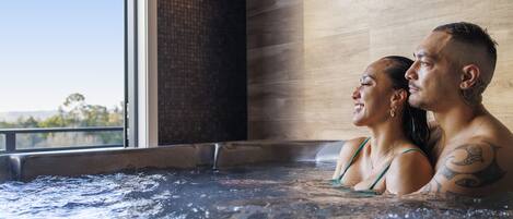 A couple in a hot tub with a view of the outdoors.