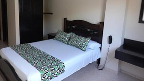 Une chambre à coucher avec un lit, une table de chevet et un téléphone fixé au mur.
