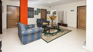 Un hall d’hôtel avec un canapé bleu, une table basse et un vase décoratif.
