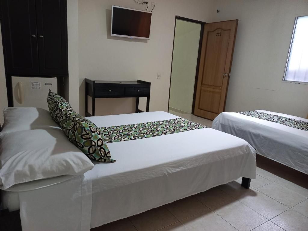 A bedroom with two beds, a desk, a wardrobe, and a television.