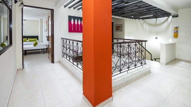 Un hall d’hôtel avec un escalier, un lit en arrière-plan et un tableau accroché au mur.