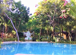 A swimming pool surrounded by lush greenery and a statue. - Xolumado Inspiration Village by Karisma (Playa del Carmen)