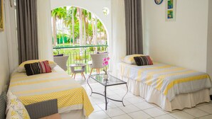 Une chambre d’hôtel avec deux lits, une table en verre et une vue sur un jardin verdoyant.