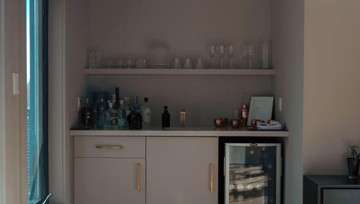 A minibar with various bottles and glasses, a small refrigerator, and a glass display case.