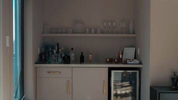A minibar with various bottles and glasses, a small refrigerator, and a glass display case.