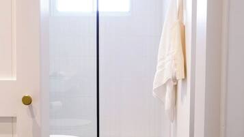 Een badkamer met een witte deur, een handdoek aan de muur en een raam boven de deur.