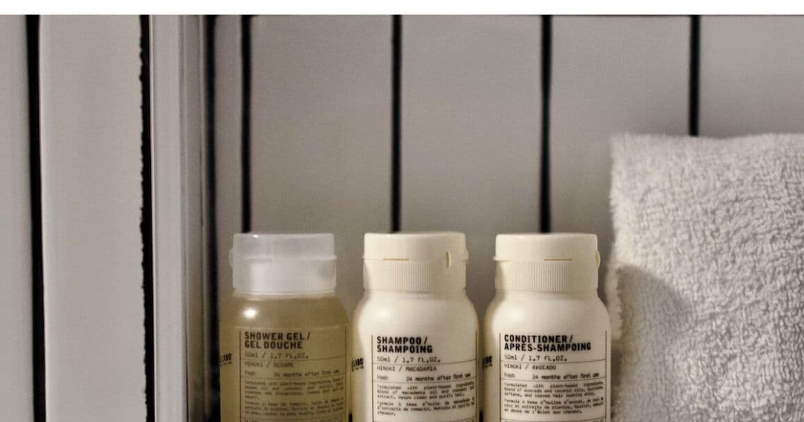 Tres botellas de gel de ducha, champú y acondicionador sobre una estantería.