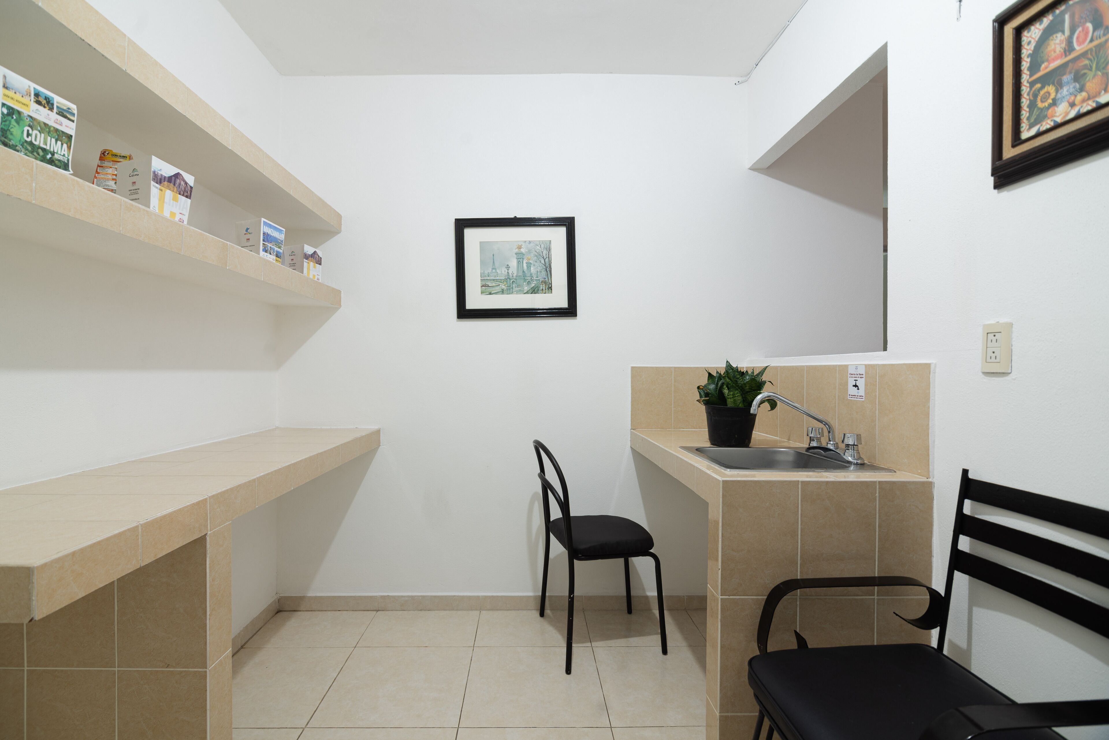 A small kitchen with a sink, a chair, and a shelf with food items.