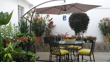 An outdoor patio with a round table, yellow cushioned chairs, and a large umbrella.