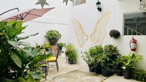 A patio area with potted plants, a table with chairs, and a wall mural of wings.