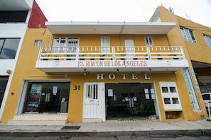 A hotel named "El Rincon de Los Angeles" with a yellow facade, white balconies, and a visible entrance.