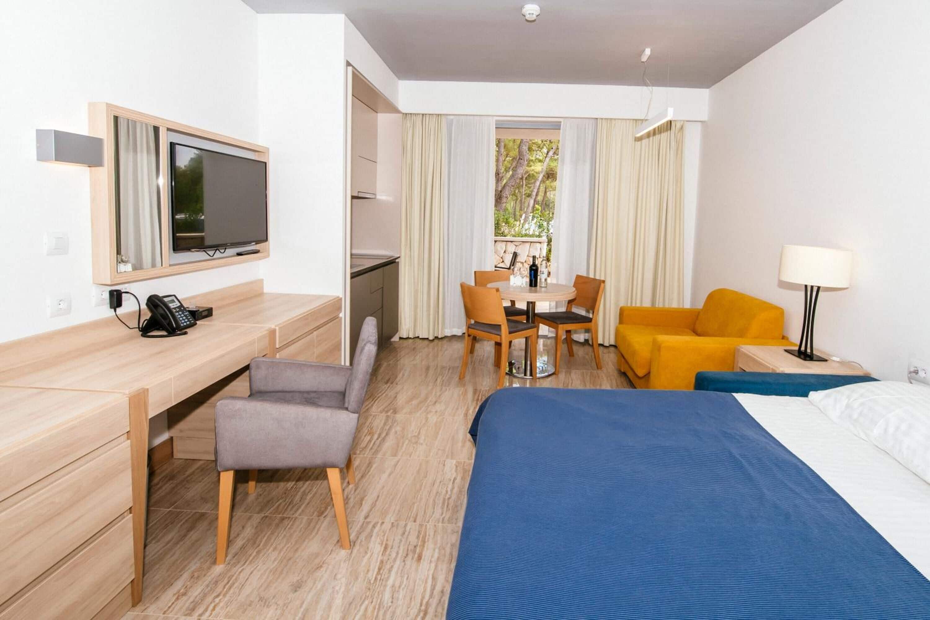Ein Hotelzimmer mit Bett, Schreibtisch, Stuhl, Tisch und Fernseher.