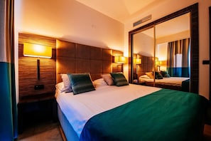 A hotel room with a large bed, two bedside lamps, a mirror, and a headboard with a textured design. - Zaton Holiday Resort (Nin)