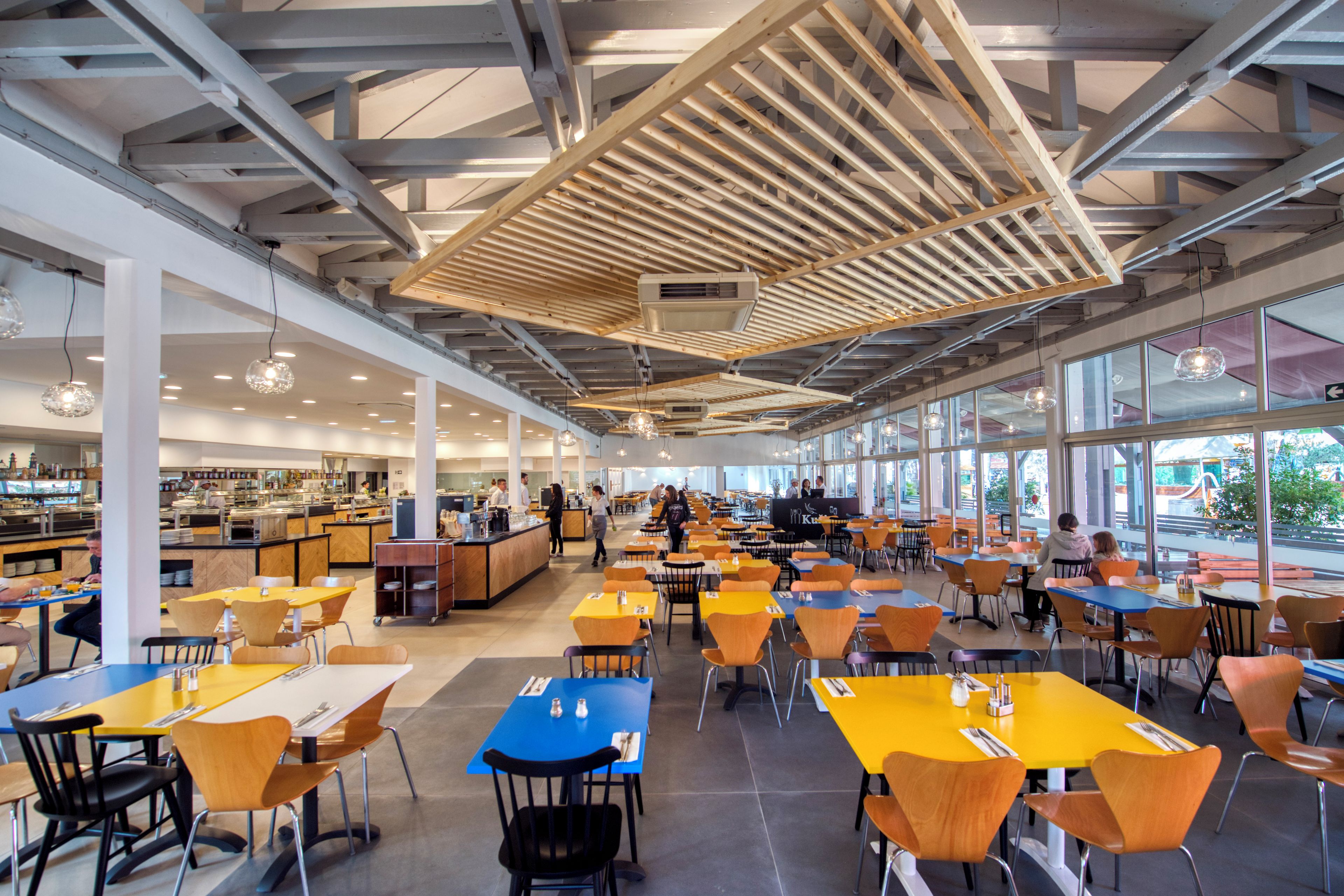 Una amplia cafetería con techos altos, ventanas grandes y diversas opciones de asientos.