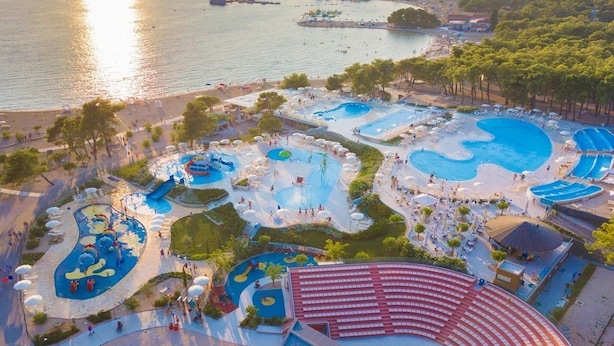 Un resort con varias piscinas, una playa y vista al mar.