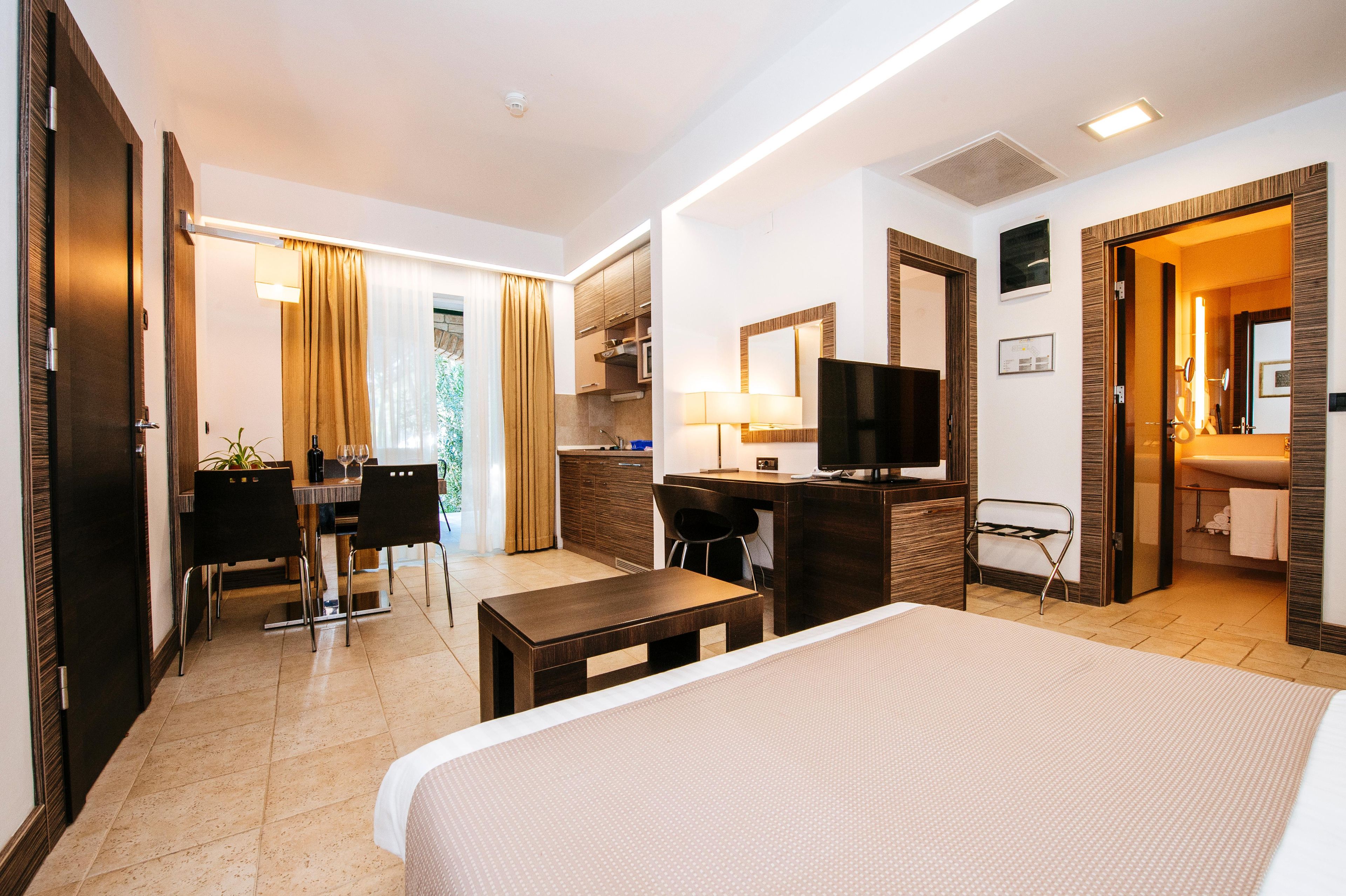 Una habitación de hotel con cama, escritorio, televisor y baño.