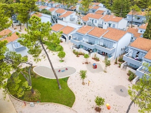 Houses with flat roofs and light exteriors are arranged in a grid, surrounded by trees and shrubs.