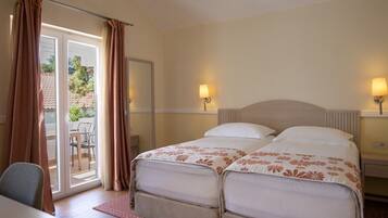 A double room with two beds, a table, and a chair.