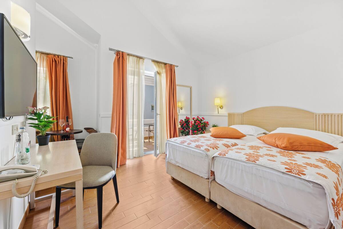 Una habitación de hotel con una cama, un escritorio con teléfono, una silla y una mesa con una planta.