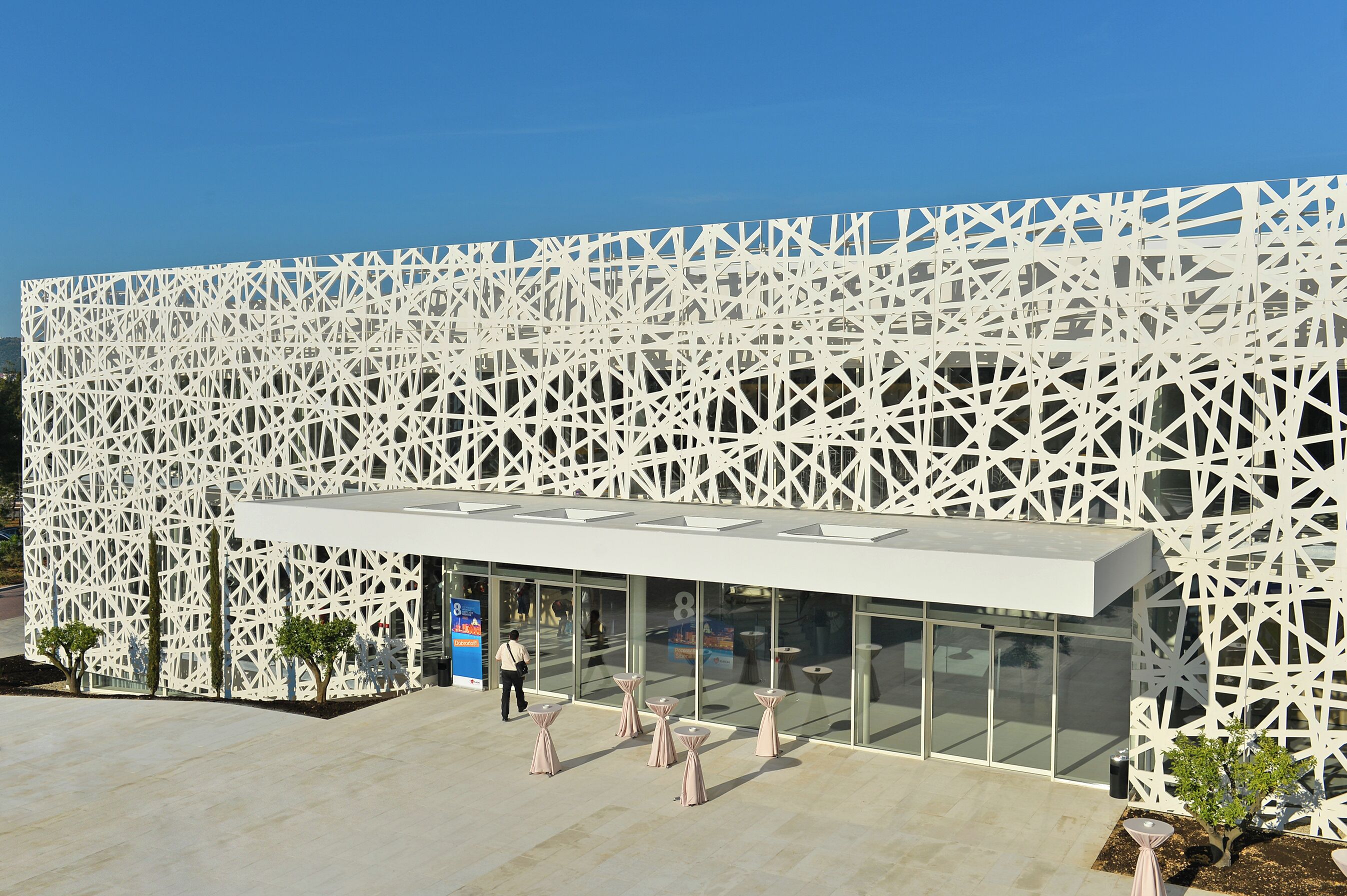 Een modern gebouw met een witte gevel van latten en grote glasramen.