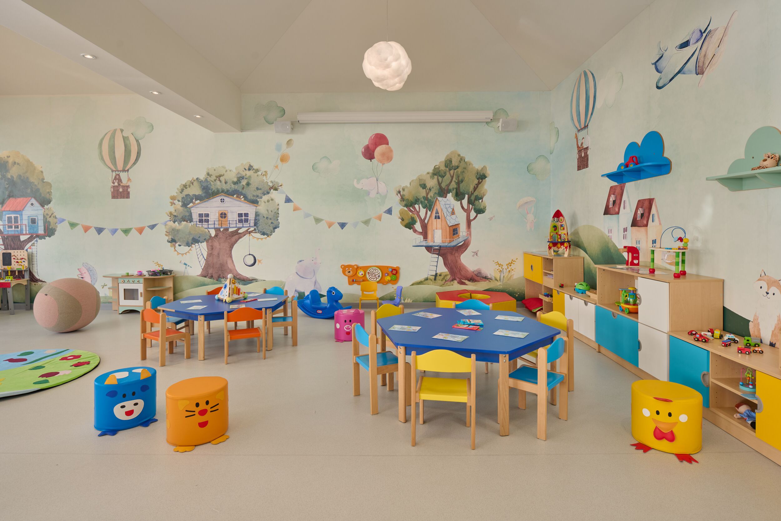 A children's playroom with colorful furniture, educational toys, and whimsical wall decorations.
