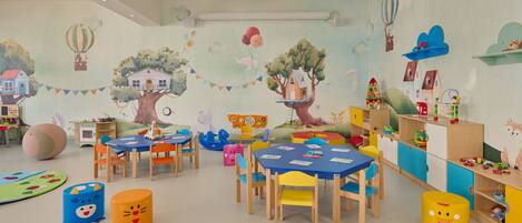 A children's playroom with colorful furniture, educational toys, and whimsical wall decorations.