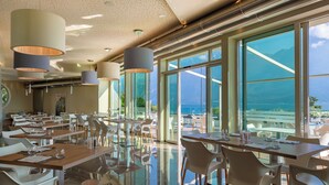 A modern dining area with large windows, reflective floors, and contemporary lighting fixtures. - Hotel Atilius Adults Only (Limone sul Garda)