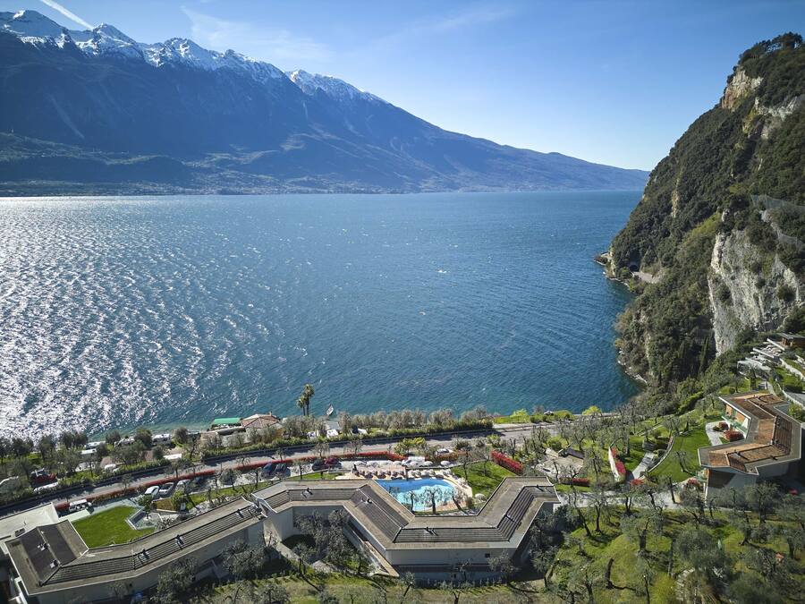 Un complejo turístico con piscina, rodeado de exuberante vegetación y con montañas al fondo.