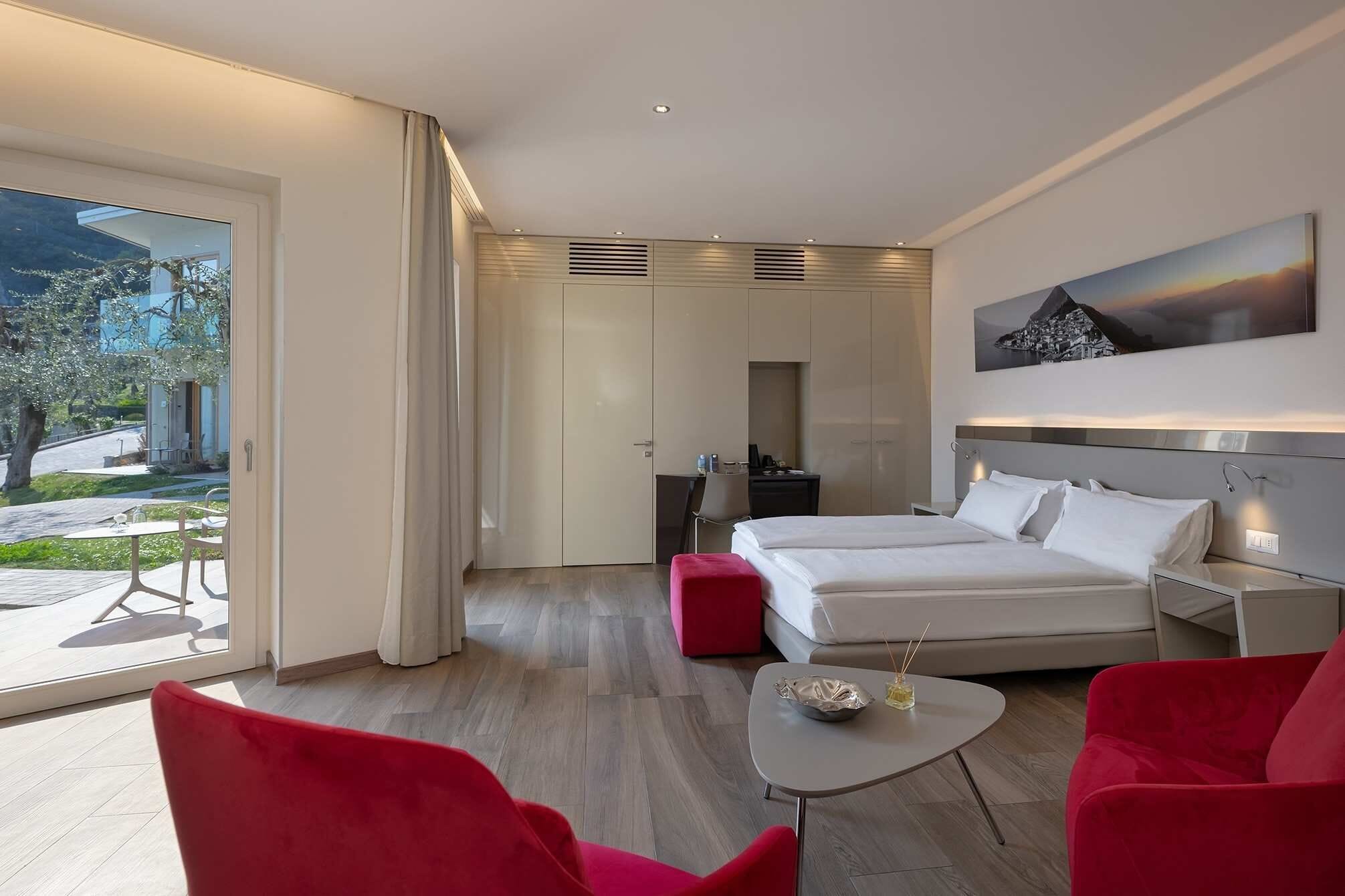 A modern hotel room with a bed, a desk, a chair, and a dining table.