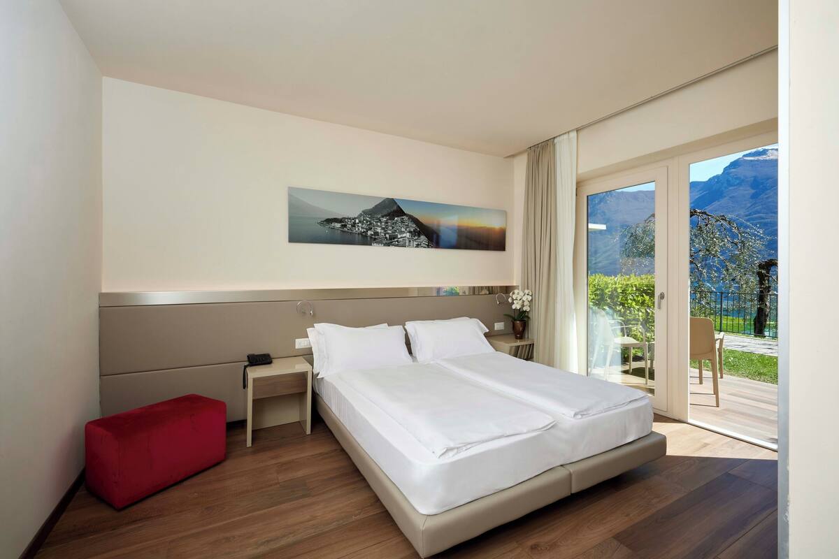 Ein modernes Hotelzimmer mit einem Bett, einer roten Bank, einem Nachttisch und einem Stadtbild.