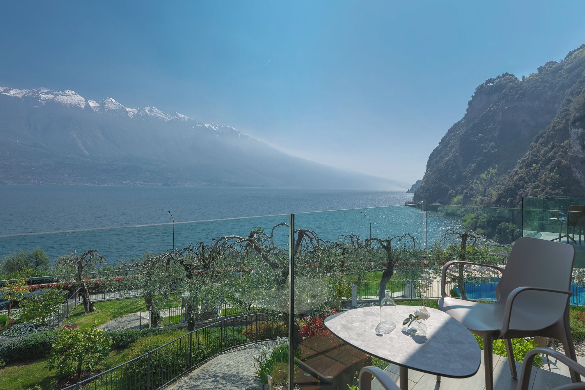 Terraza con mesa y sillas con vista a un lago y montañas al fondo.